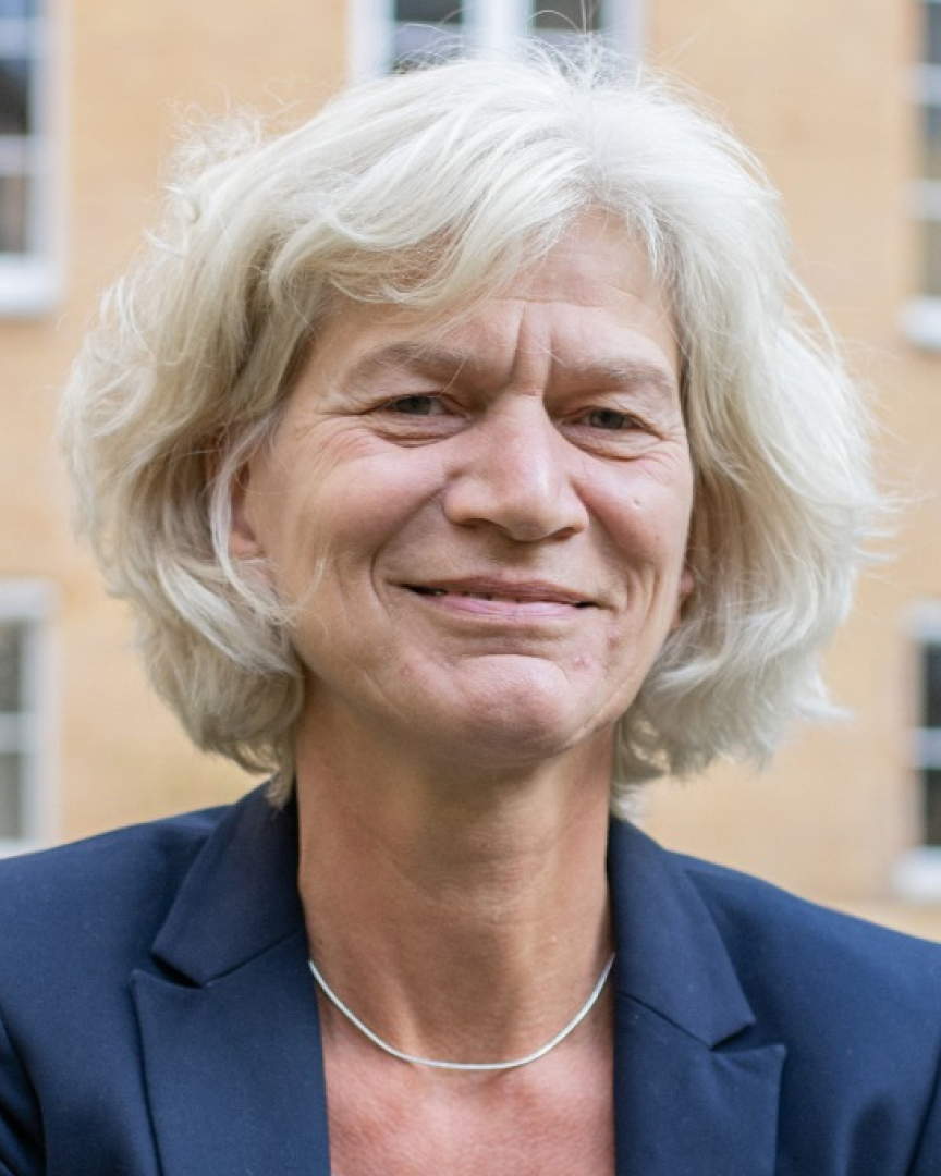 Eine Frau im Jackett, die in die Kamera lächelt.