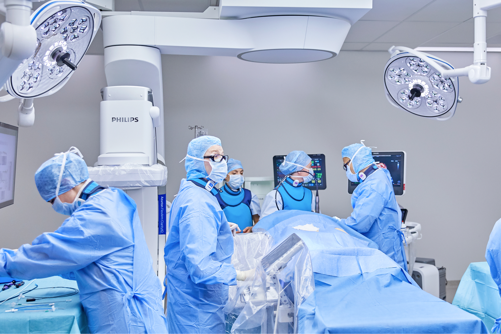 Chirurgisches Team in blauer Kleidung arbeitet an einem Patienten in einem Operationssaal.