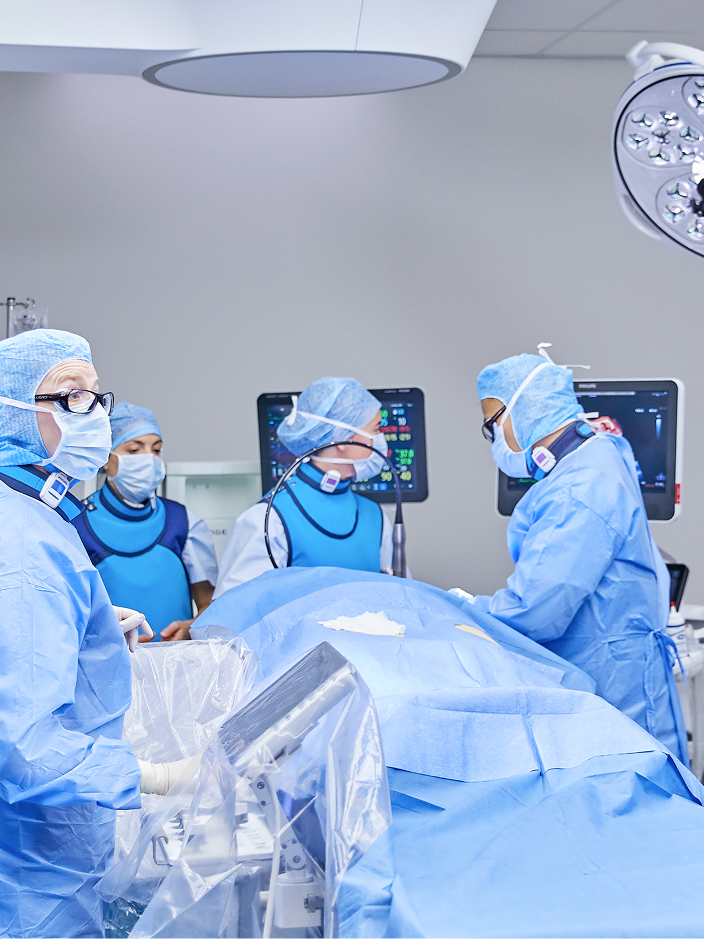 Ein Team von Chirurgen mit blauen OP-Kitteln und Masken arbeitet konzentriert an einem Patienten auf einem Operationstisch.