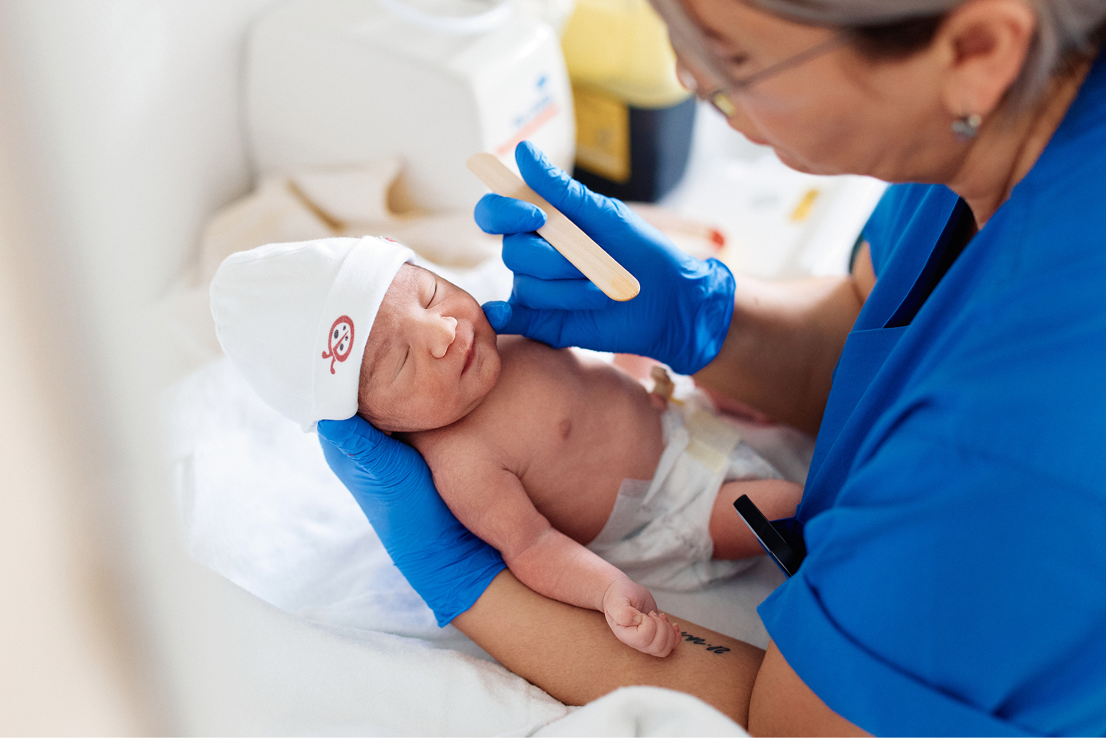 Ein Neugeborenes wird von einer Person mit blauen Handschuhen untersucht.