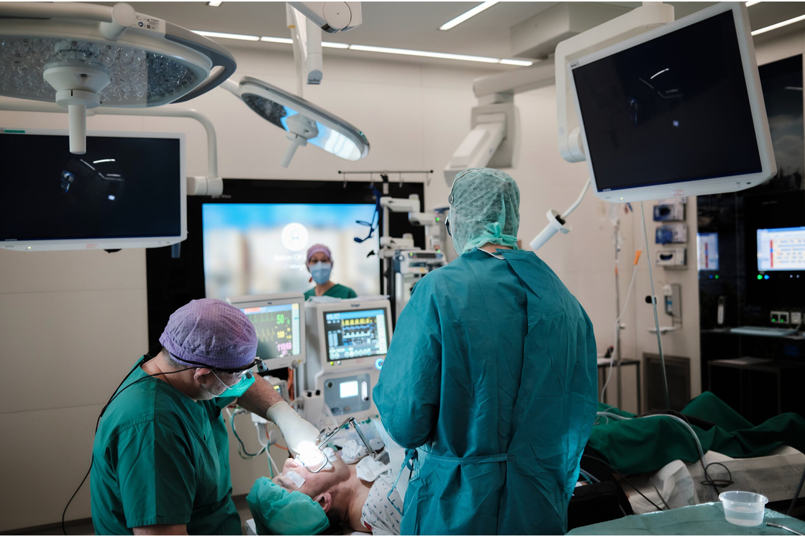 Chirurgisches Team in einem Operationssaal, umgeben von Monitoren und medizinischen Geräten.