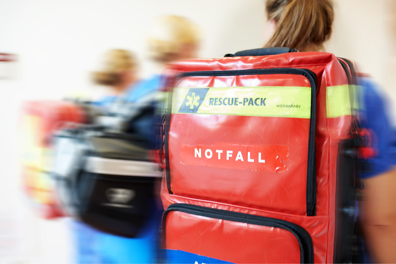 Eine Sanitäterin trägt eine rote Notfalltasche mit der Aufschrift 