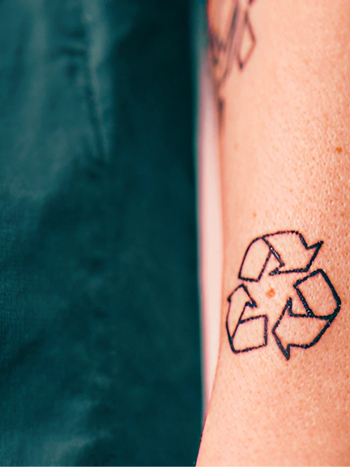 Tattoo eines Recyclingsymbols auf einem Unterarm.