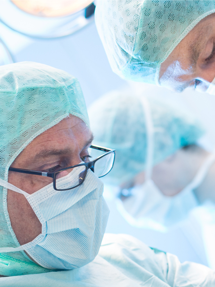 Chirurgen in OP-Kleidung und Masken konzentrieren sich auf einen Eingriff im Operationssaal.
