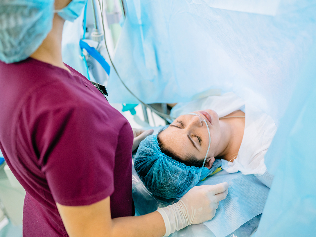 Medizinisches Personal in Schutzkleidung betreut Patientin während eines Eingriffs im Operationssaal
