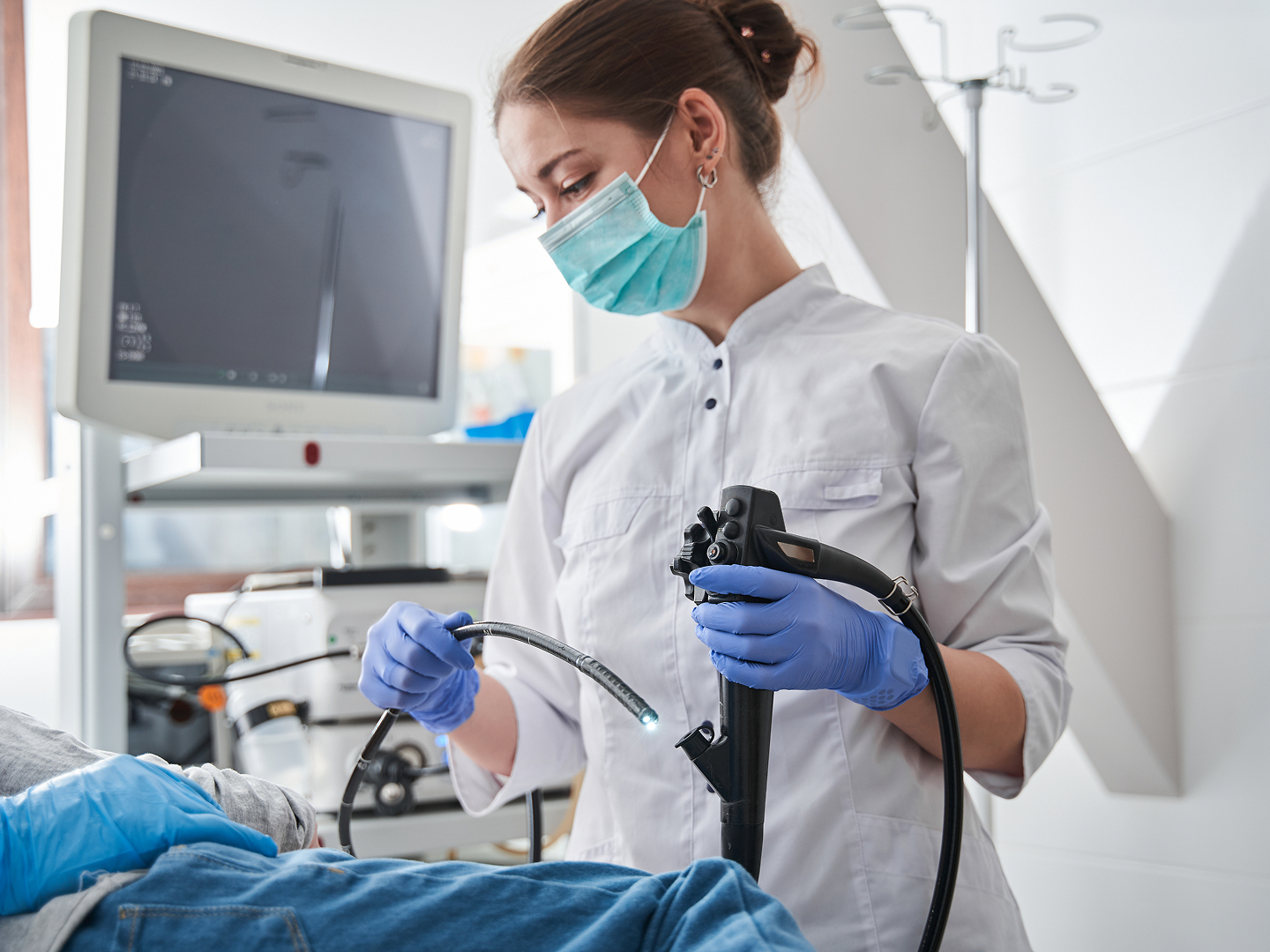 Eine medizinische Fachkraft in Schutzkleidung führt einen Eingriff mit einem Endoskop an einem Patienten durch.