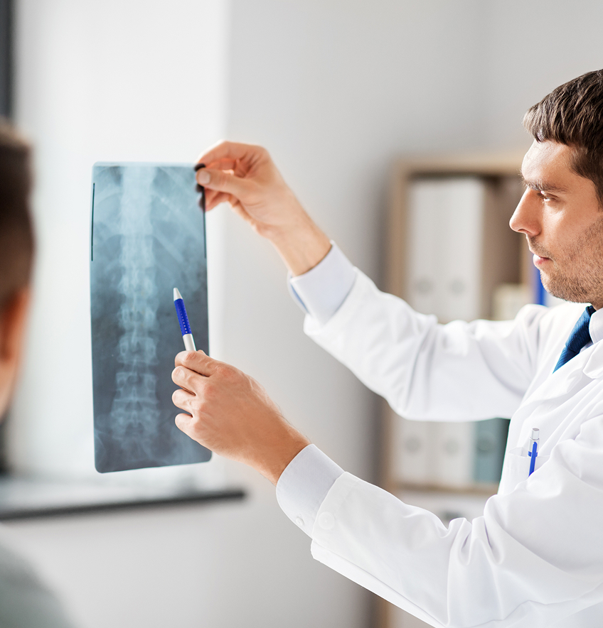 Arzt zeigt Röntgenbild einer Wirbelsäule und erklärt es einem Patienten.