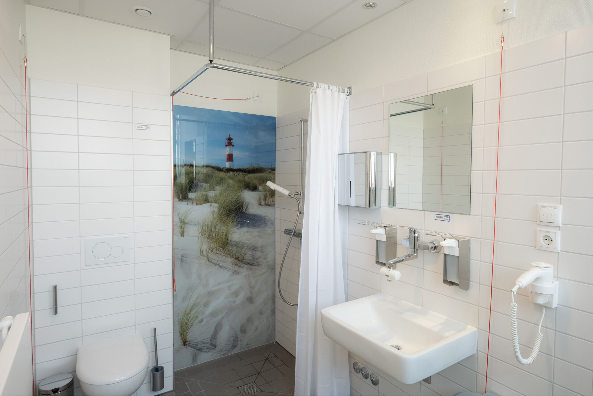 Modernes Badezimmer mit Dusche, Waschbecken, Toilette und einem Bild von einem Leuchtturm an der Wand.