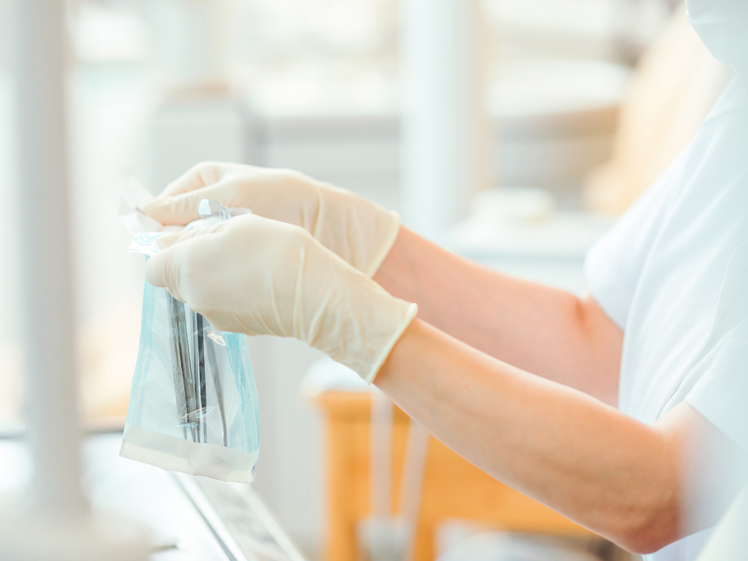 Eine Person in Gummihandschuhen hält einen durchsichtigen Beutel mit medizinischen Instrumenten.
