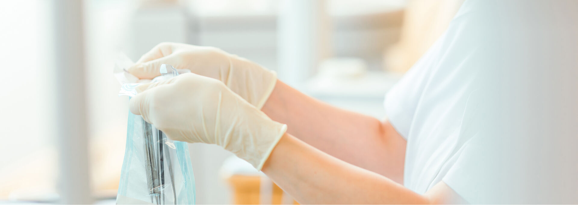 Eine Person in Gummihandschuhen hält einen durchsichtigen Beutel mit medizinischen Instrumenten.