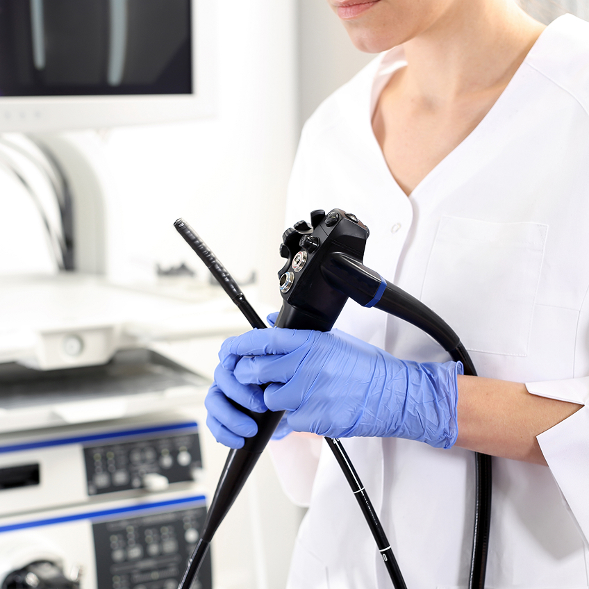 Eine Person in Handschuhen hält ein medizinisches Endoskop in einer klinischen Umgebung.
