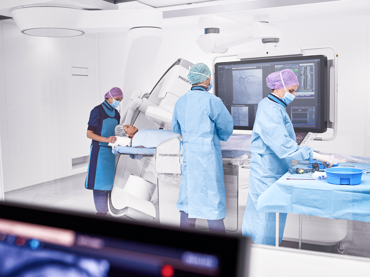 Medizinisches Team in OP-Kleidung arbeitet an einem Patienten in einem modernen Operationssaal mit medizinischen Geräten.