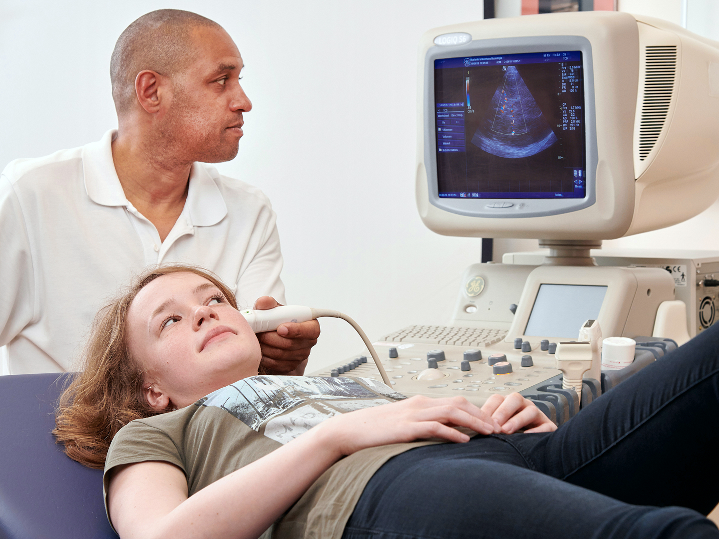 Ein Arzt führt einen Ultraschall bei einer liegenden Patientin durch.
