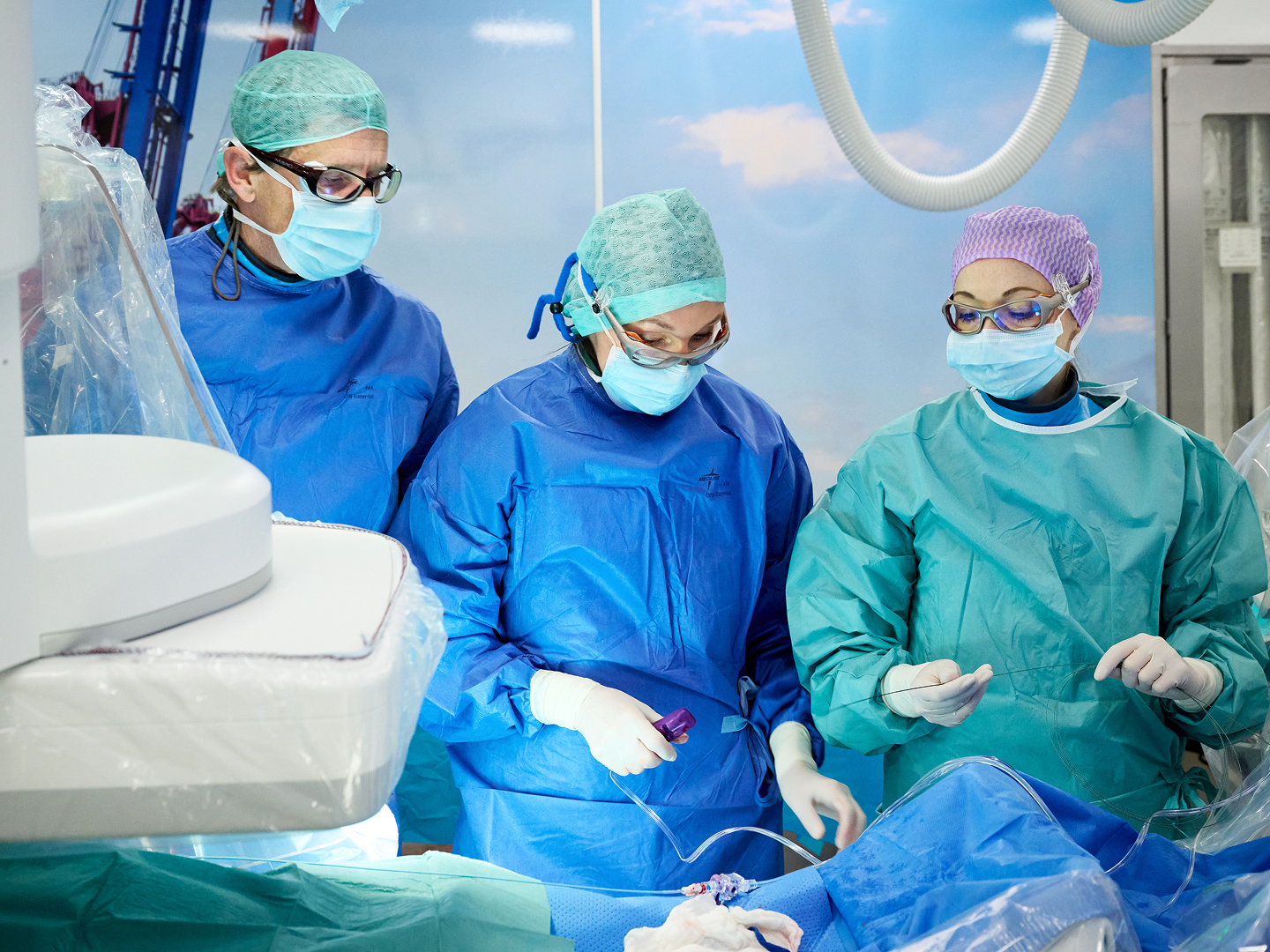 Drei Chirurgen mit blauen OP-Kitteln und Masken arbeiten konzentriert an einem Patienten auf einem Operationstisch.