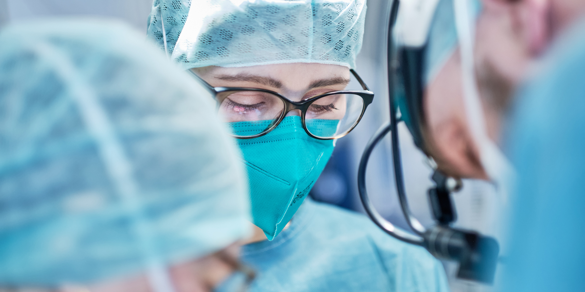 Chirurgen mit Schutzkleidung führen konzentriert eine Operation durch.