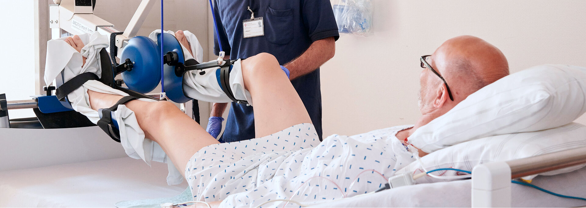 Ein Physiotherapeut hilft einem Patienten, dessen Bein während einer Behandlung in einer Schiene steckt.