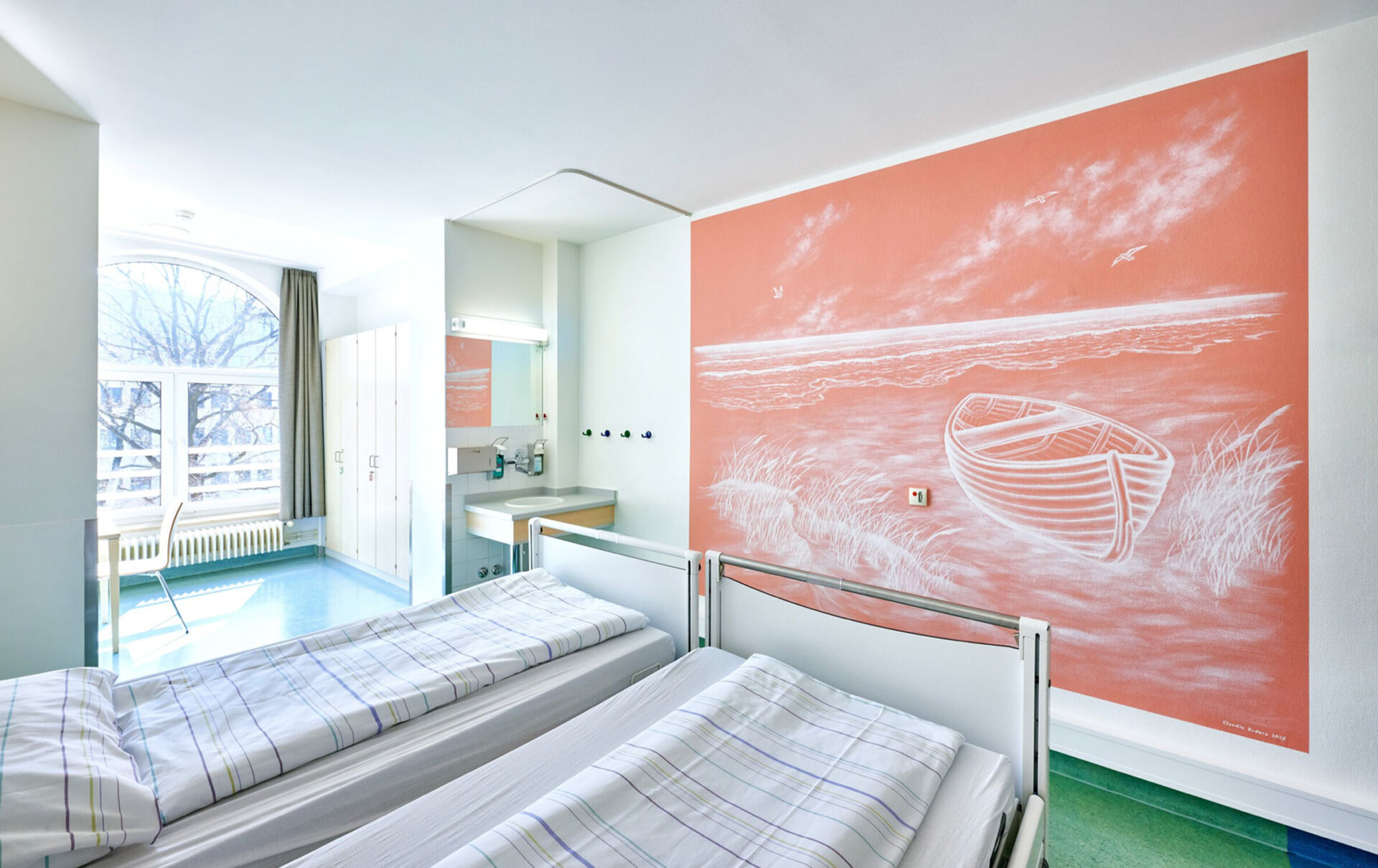 Helles Zimmer mit zwei Betten, einem großen Fenster und einer Wandmalerei eines Bootes auf korallenfarbenem Hintergrund.