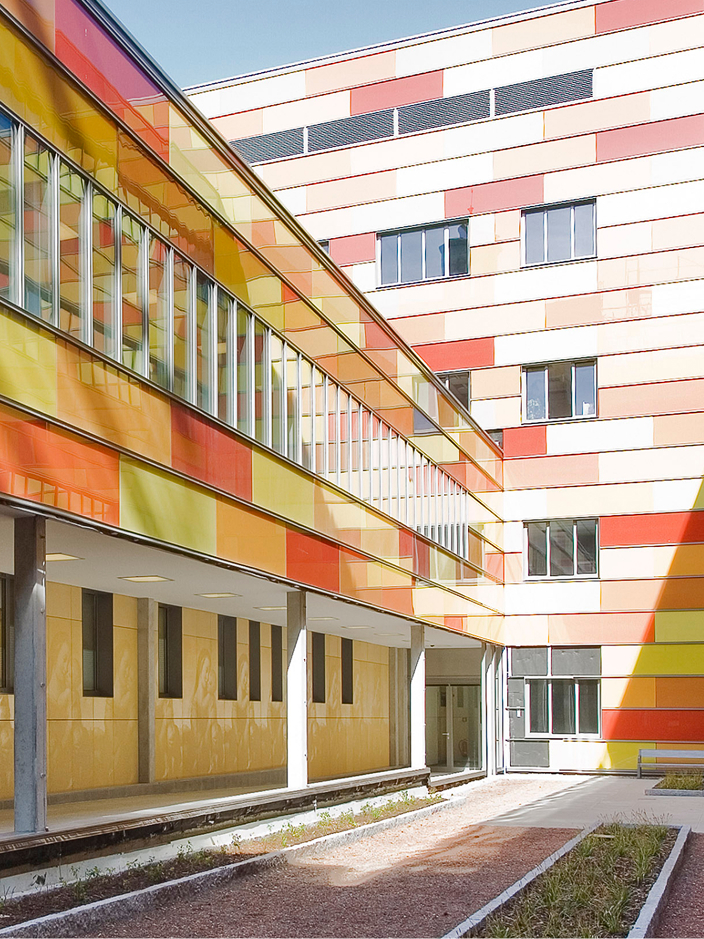 Blick auf ein Gebäude mit einer Kachelfassade in Gelb, Orange und Rot.