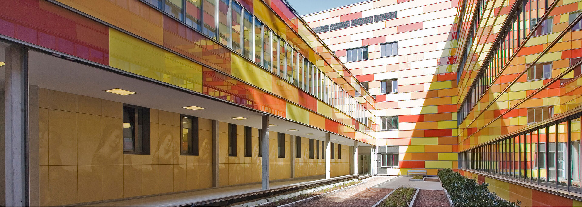 Blick auf ein Gebäude mit einer Kachelfassade in Gelb, Orange und Rot.