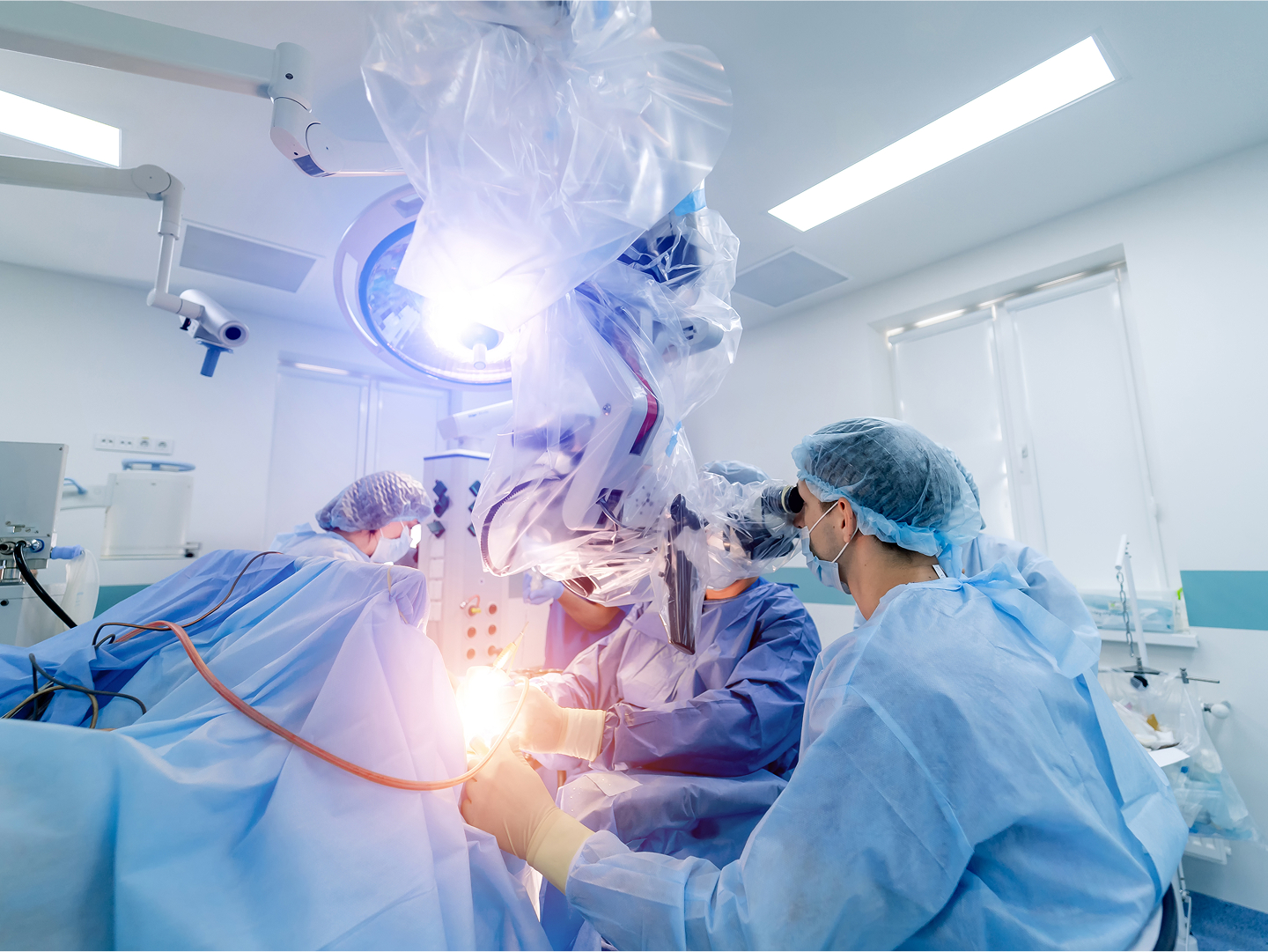 Chirurgisches Team mit einem Roboterarm und medizinischen Geräten in einem Operationssaal.