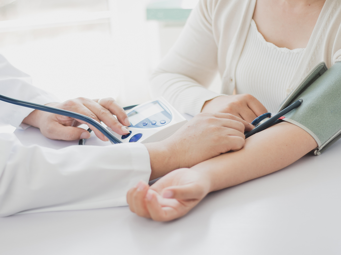 Ein Arzt misst den Blutdruck einer Patientin mit einem Blutdruckmessgerät.