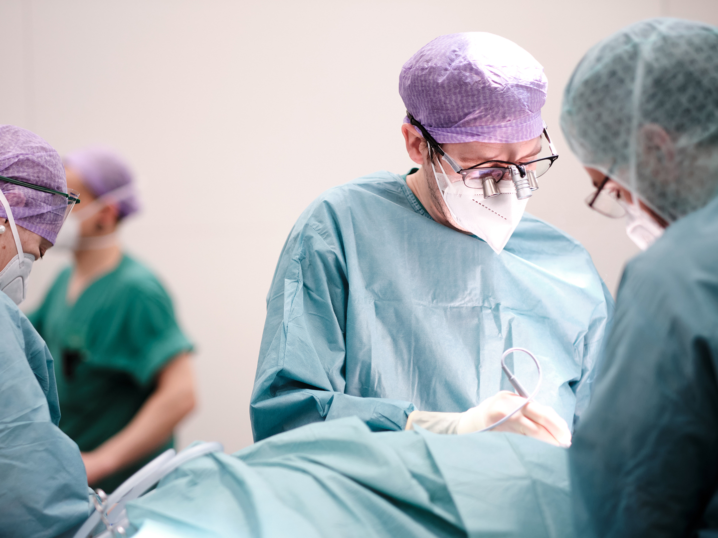 Chirurgisches Team in OP-Kleidung führt einen Eingriff durch, konzentriert auf die Operation.