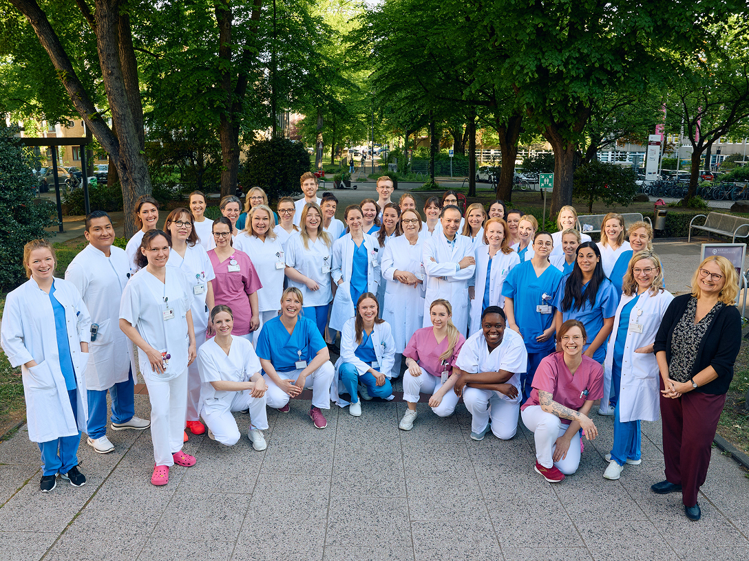 Gruppe von medizinischem Personal in Arbeitskleidung, die im Freien für ein Foto posiert.