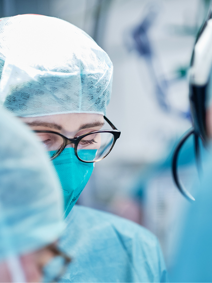 Chirurgisches Team in blauer Kleidung und Schutzmasken, konzentriert bei einer Operation.