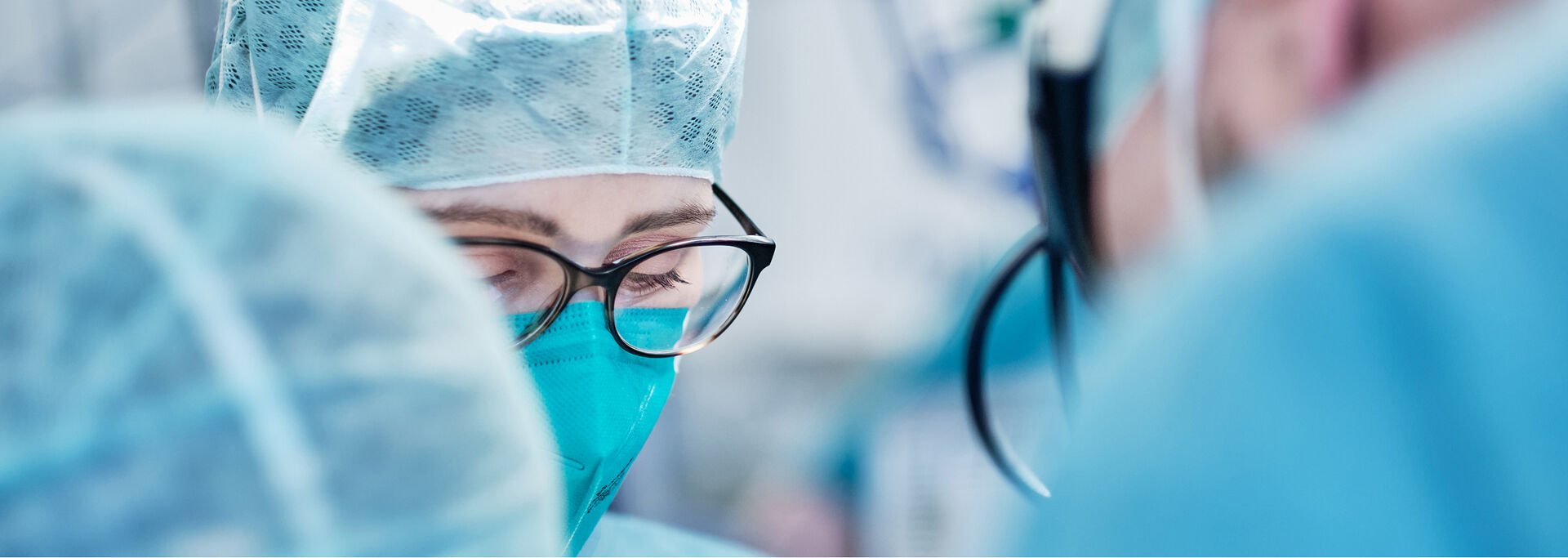 Gruppe von medizinischem Personal in blauer und weißer Arbeitskleidung posiert im Außenbereich der Klinik für ein Foto.