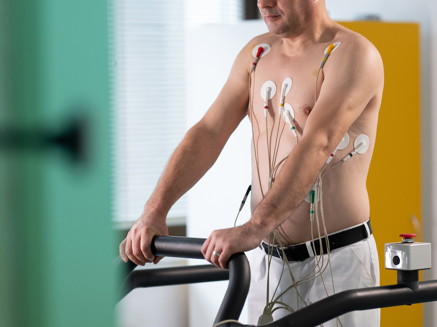 Mann auf einem Laufband mit Elektroden auf der Brust, zur medizinischen Untersuchung.