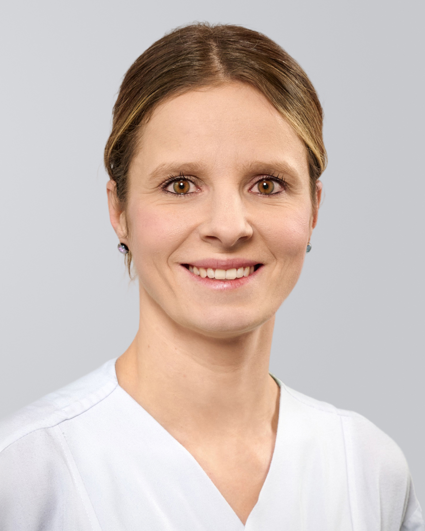 Lächelnde Frau in weißer Kleidung vor einem neutralen Hintergrund.