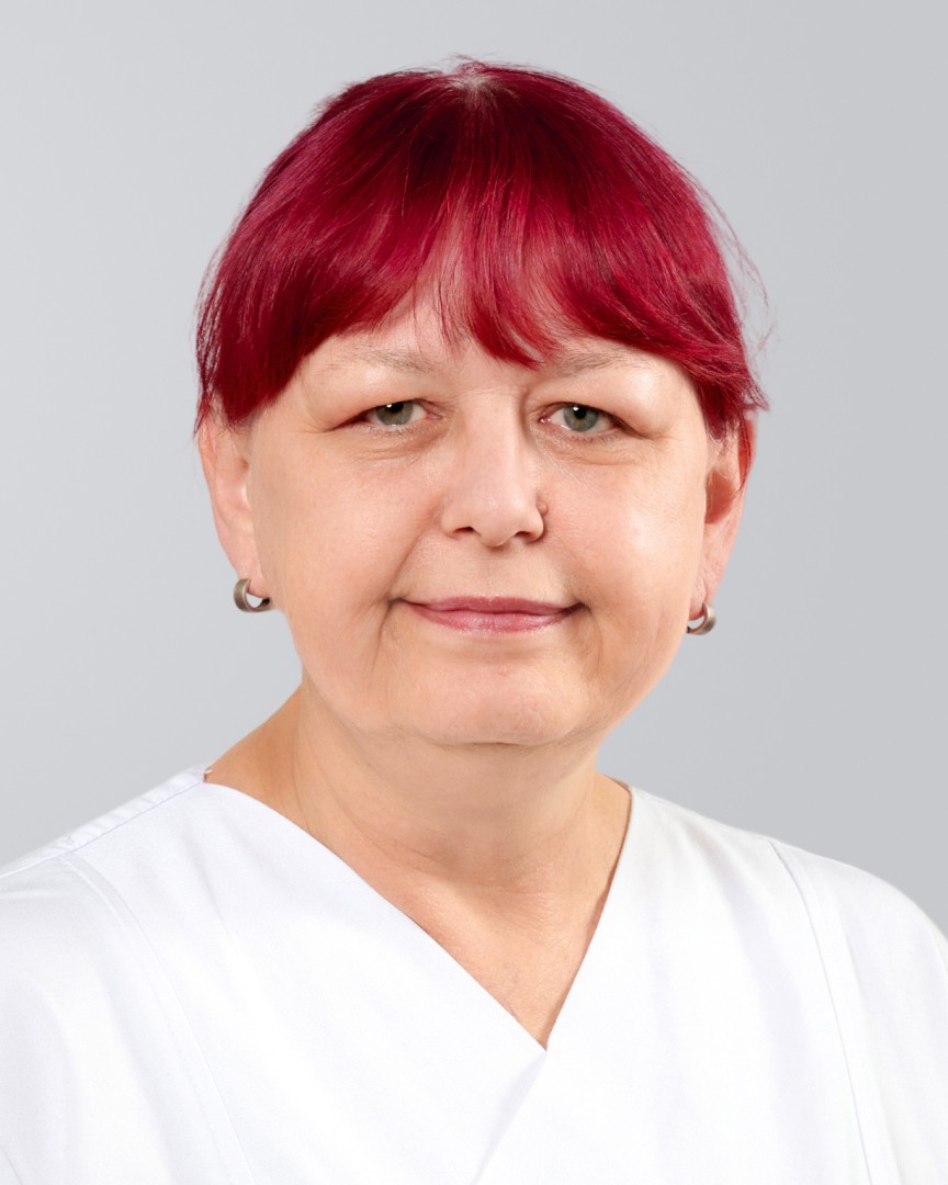 Frau mit rotem Haar in weißer Kleidung vor grauem Hintergrund.