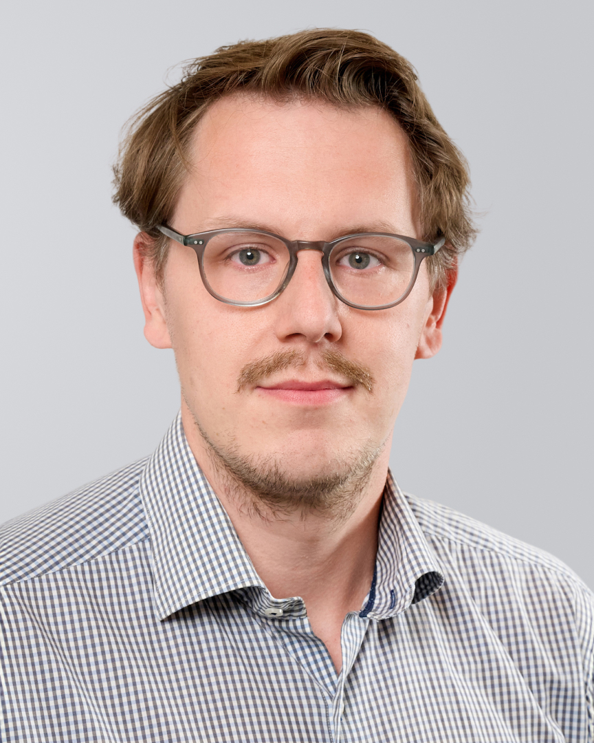 Mann mit Brille und kariertem Hemd vor neutralem Hintergrund.