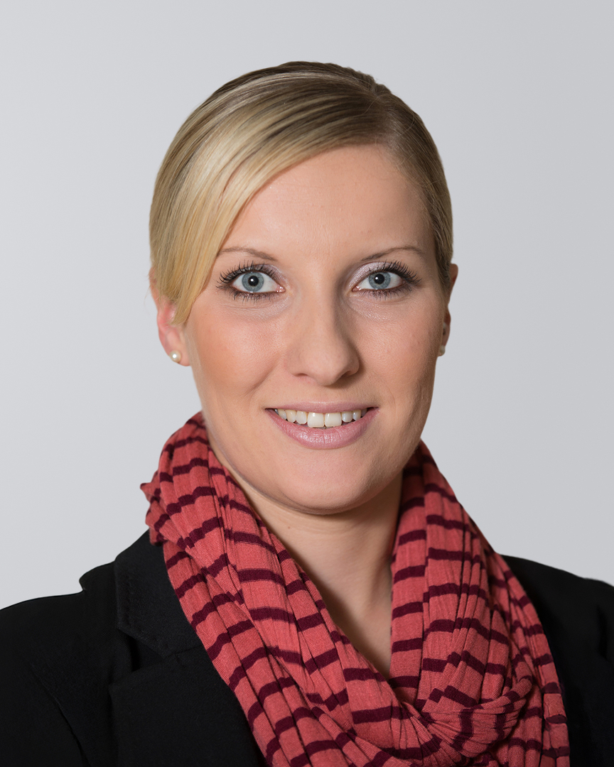 Frau mit blonden Haaren und einem gestreiften roten Schal vor einem neutralen Hintergrund.